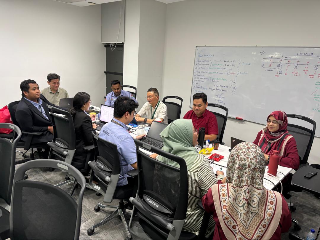 Round-table working session with team members on laptops, beside a whiteboard listing EIS module go-live items and completion percentages.